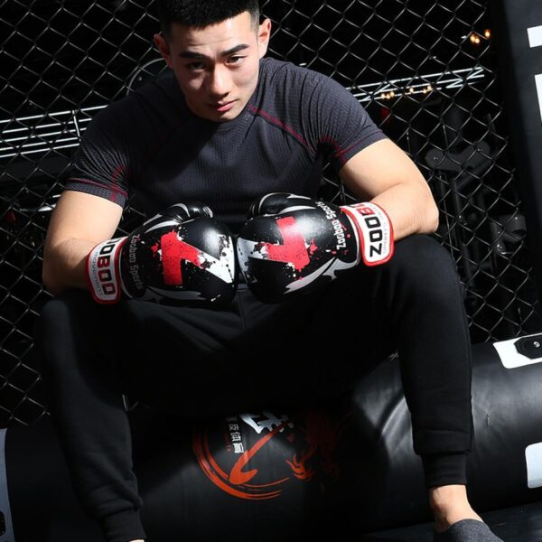 A fit man sitting down wearing a black 100 Spartans® Boxing Gloves by zooboo sport