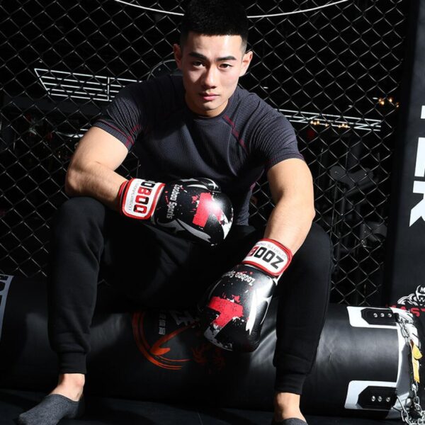 A fit man sitting down wearing a black 100 Spartans® Boxing Gloves by zooboo sport