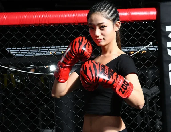 A lady in the ring wearing red tiger stripes boxing gloves