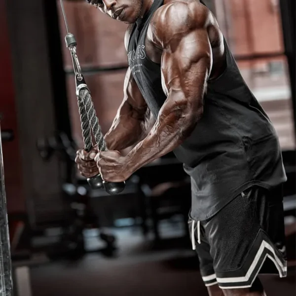 A black man working out in the gym, wearing a black mens tank top and black gym shorts sold by 100 Spartans