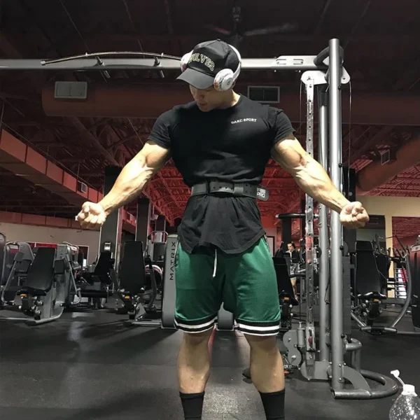 A body builder wearing a black t-shirt and a green gym shorts sold by 100 Spartans