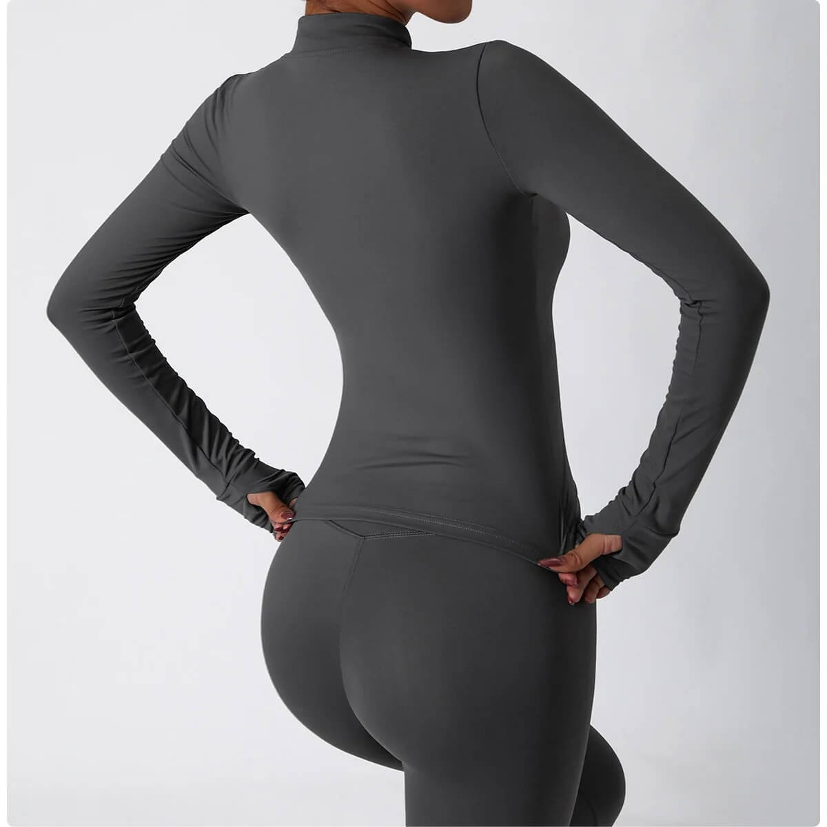 The back view of a woman wearing a dark gray 3 piece womens tracksuit sold by 100 spartans