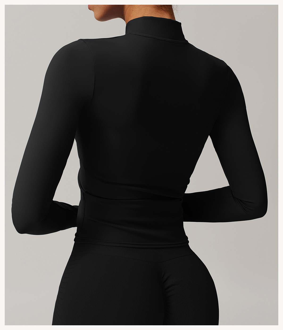 The back view of a woman wearing a black 3 piece womens tracksuit sold by 100 spartans