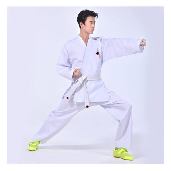 A man practicing karate while wearing a white 9.5oz Kumite Karate Uniform sold by 100 Spartans